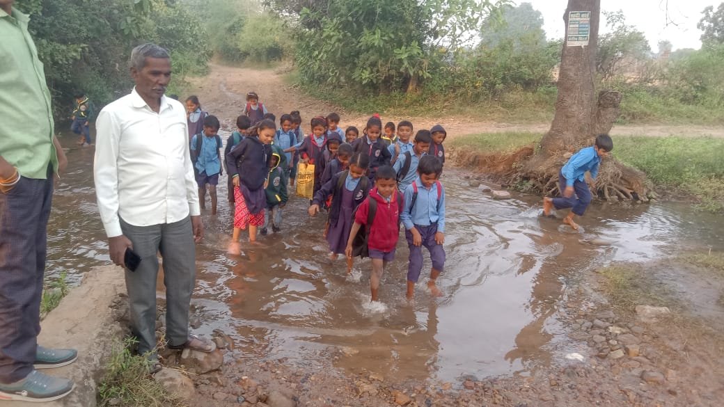 Shameful image: Schoolchildren risk their lives crossing a submerged road in Dhai village.
